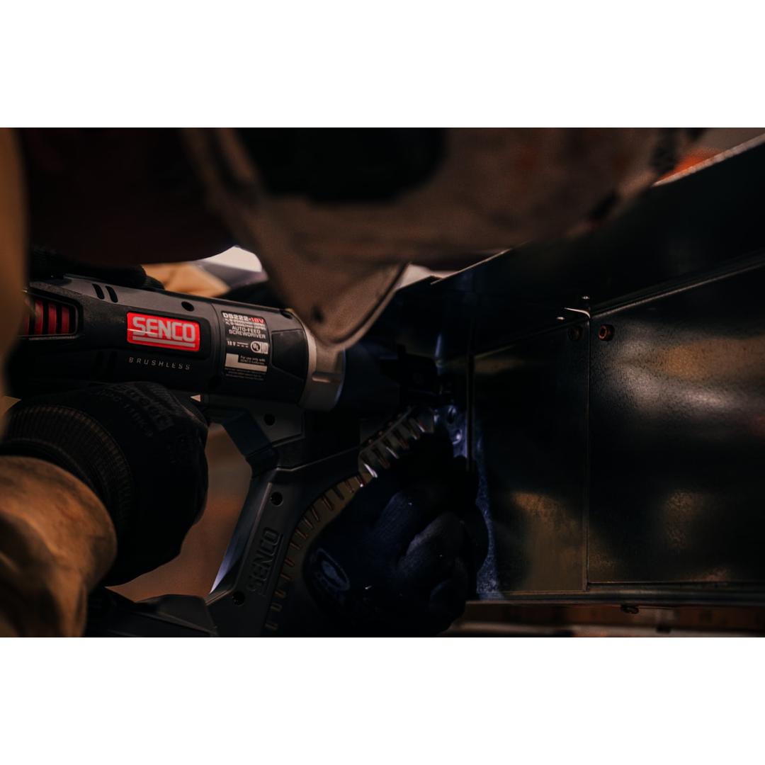 Visseuse en bande sur batterie DURASPIN DS722-18V SENCO — Visseuse en bande SENCO DS722-18V tenue par une main gantée contre un caisson métallique noir