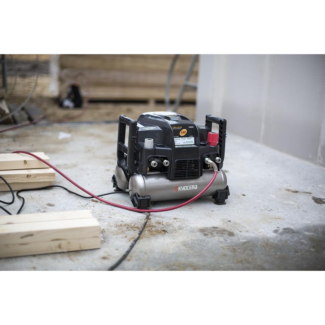 Compresseur HAUTE PRESSION 9/20 2x4,5l - 42 bar TJEP — Compresseur TJEP 9/20 HP en situation sur une dalle de chantier, flexible d'air rouge raccordé et câble secteur déroulé, tasseaux de bois au premier plan