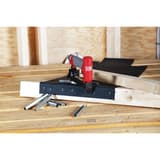 Agrafeuse pneumatique SFT10XP B SENCO — Agrafeuse SENCO SFT10XP B en atelier, posée sur un pare-vapeur noir agrafé sur une poutre bois