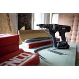 Visseuse en bande sur batterie DURASPIN DS525-18V SENCO — Visseuse en bande SENCO DS525-18V posée sur un établi, bande de vis chargée et cartons de recharges