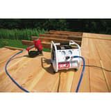 Compresseur SENCO AC10304 discret sans huile SENCO — Compresseur SENCO AC10304 sans huile en service sur une terrasse bois, cloueur pneumatique rouge raccordé