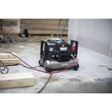 Compresseur HAUTE PRESSION 9/20 2x4,5l - 42 bar TJEP — Compresseur TJEP 9/20 HP en situation sur une dalle de chantier, flexible d'air rouge raccordé et câble secteur déroulé, tasseaux de bois au premier plan