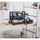 Compresseur HAUTE PRESSION 9/20 2x4,5l - 42 bar TJEP — Compresseur TJEP 9/20 HP en service sur un plateau d'échafaudage, un cloueur à rouleau TJEP raccordé posé à côté et deux flexibles rouges partant vers le chantier